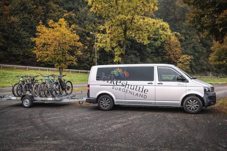 Bikeshuttle Burgenland - Bequem zum Start – direkt ins Abenteuer Bikeshuttle-Bus der Burgenland Trails mit Fahrradanhänger, bereit zur Abfahrt im herbstlichen Waldgebiet